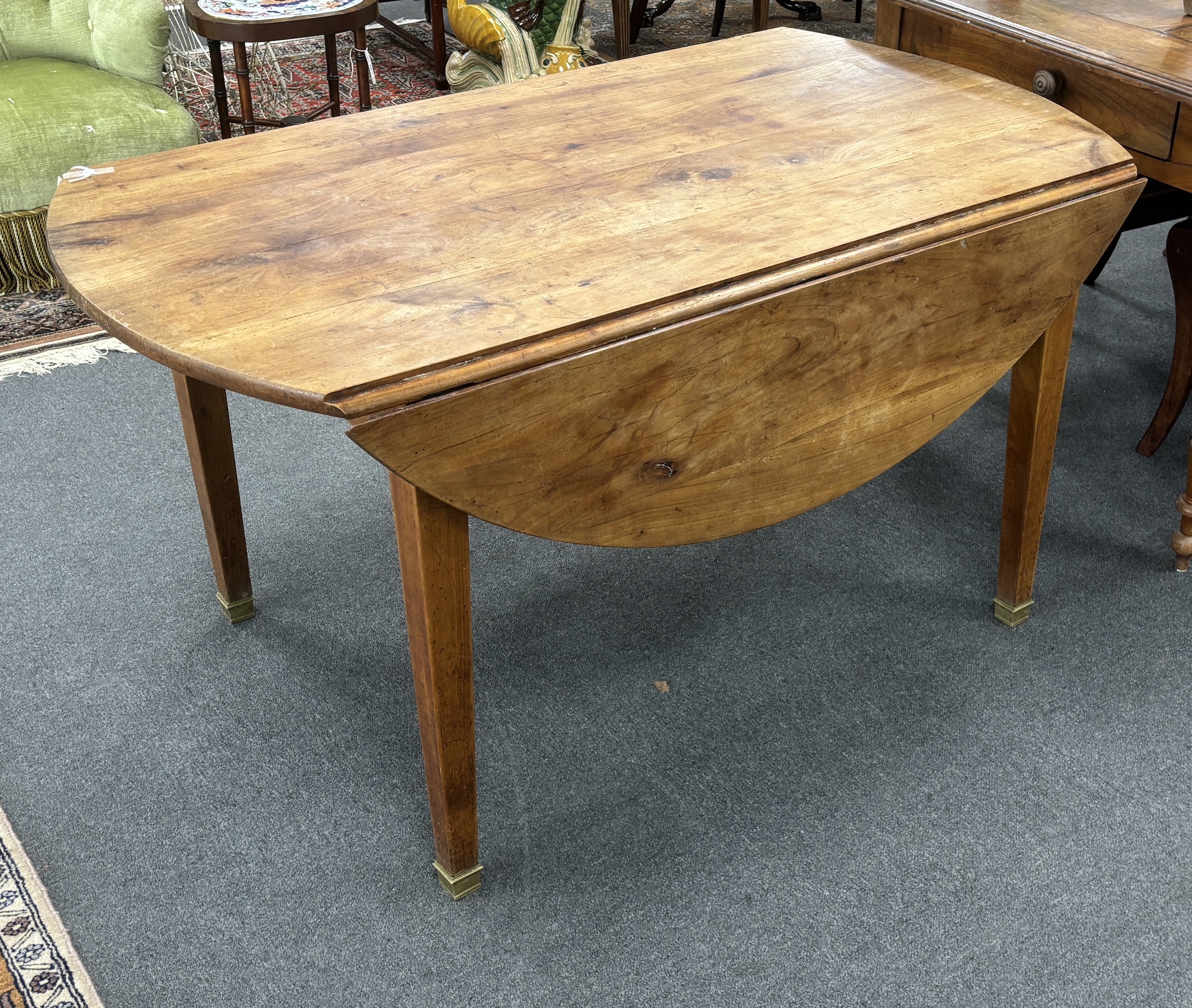 A 19th century French oval cherry drop flap kitchen table, width 136cm, depth 134cm extended, height 71cm